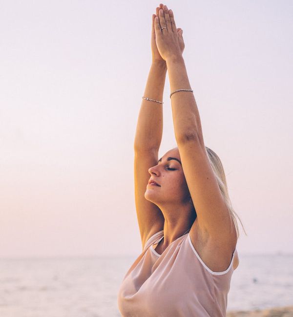 A woman stretching gracefully outdoors at sunrise, symbolizing vitality and a fresh start.